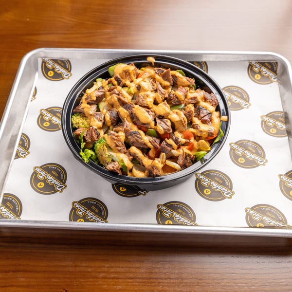 A Diablo's Tacos steak bowl with vegetables and sauce, on branded parchment paper in a metal tray.
