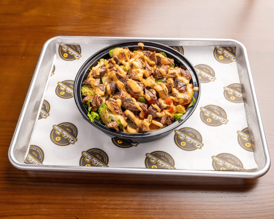 A Diablo's Tacos steak bowl with vegetables and sauce, on branded parchment paper in a metal tray.