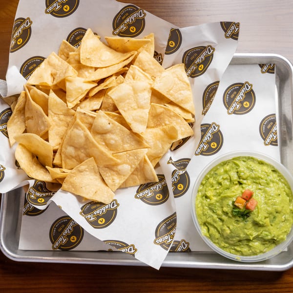 A metal tray holds a basket of Diablos Tacos tortilla chips and a bowl of guacamole.