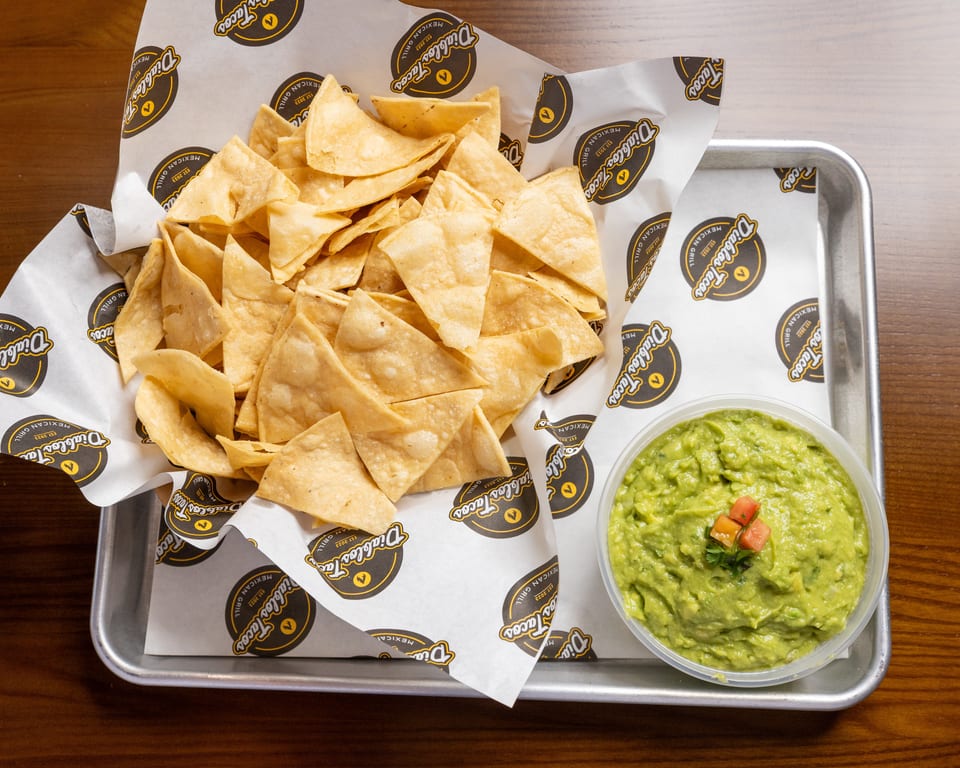 A metal tray holds a basket of Diablos Tacos tortilla chips and a bowl of guacamole.